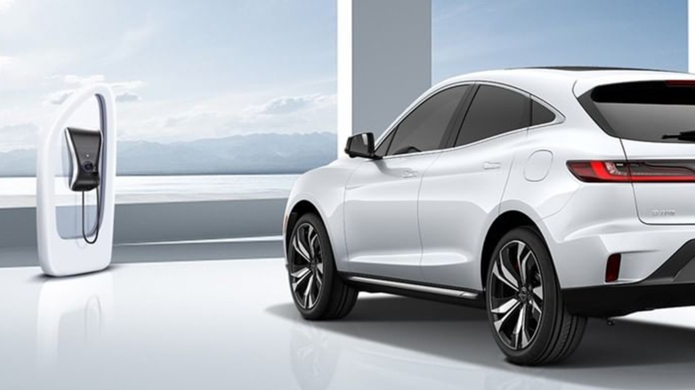 Vista trasera de vehículo eléctrico Seres 3 color blanco con una estación de carga al lado.